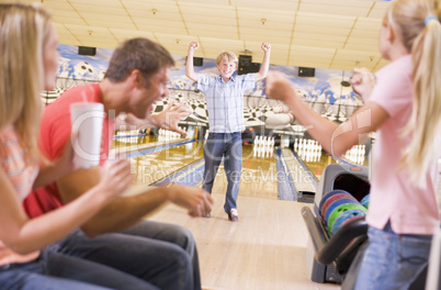 Family in bowling alley cheering and smiling