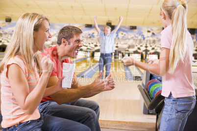 Family in bowling alley cheering and smiling