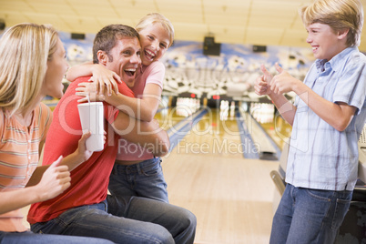 Family in bowling alley cheering and smiling