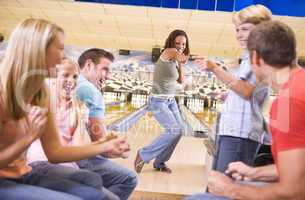 Family in bowling alley with two friends cheering and smiling