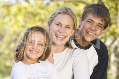 Woman with two young children outdoors smiling