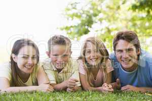 Family lying outdoors smiling