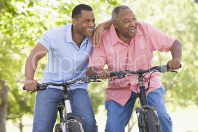 Two men on bikes outdoors smiling