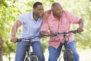 Two men on bikes outdoors smiling