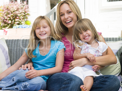 Woman and two young girls sitting on patio smiling