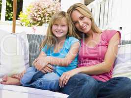 Woman and young girl sitting on patio smiling