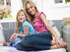 Woman and young girl sitting on patio smiling