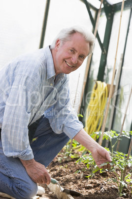 Man in greenhouse holding shovel smiling