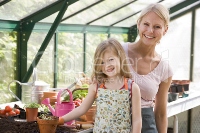 Young girl and woman in greenhouse smiling