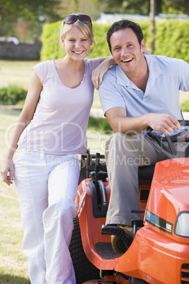 Couple outdoors with lawnmower smiling