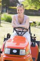 Woman outdoors with lawnmower smiling