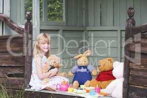 Young girl in shed playing tea and smiling