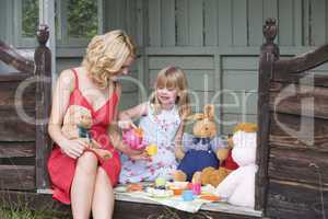 Woman and young girl in shed playing tea and smiling