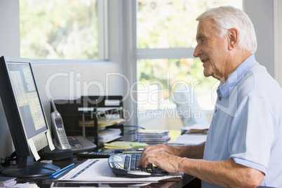 Man in home office using computer smiling