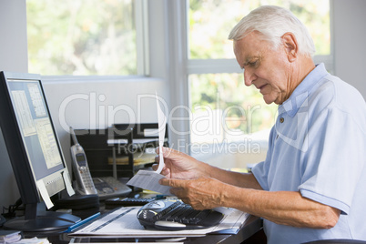 Man in home office with paperwork and computer