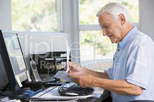 Man in home office with paperwork and computer