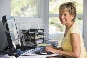 Woman in home office using computer smiling