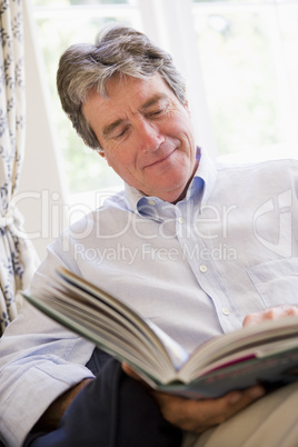 Man in living room reading book smiling