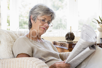 Woman in living room reading newspaper