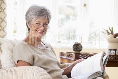 Woman in living room reading book smiling