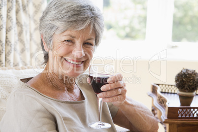 Woman in living room with glass of wine smiling