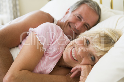 Couple lying in bed smiling