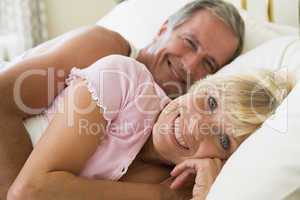 Couple lying in bed smiling