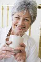 Woman in bedroom with coffee smiling