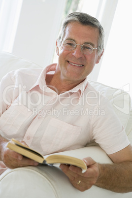 Man in living room reading book smiling