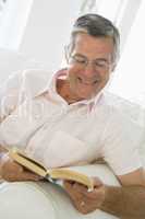 Man in living room reading book smiling