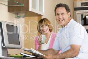Couple in kitchen with coffee and newspaper smiling
