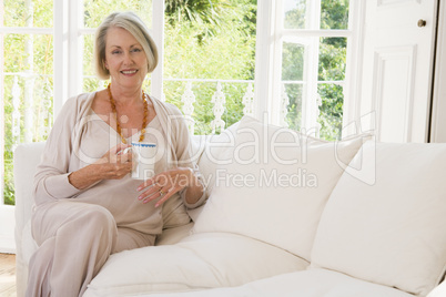 Woman in living room with coffee smiling