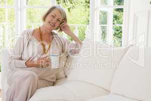 Woman in living room with coffee smiling