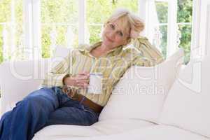 Woman in living room with coffee smiling