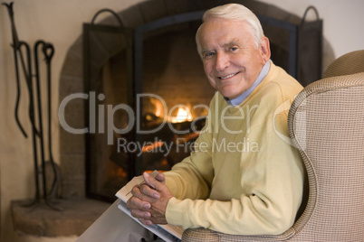 Man in living room with newspaper smiling