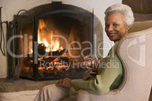 Woman in living room with drink smiling