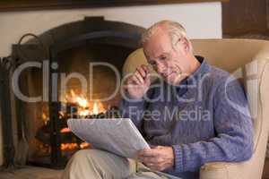 Man sitting in living room by fireplace with newspaper