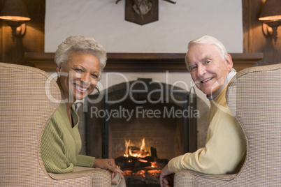 Couple sitting in living room by fireplace smiling