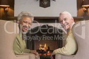 Couple sitting in living room by fireplace smiling