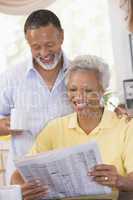 Couple relaxing with a newspaper smiling