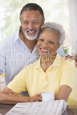 Couple relaxing with a newspaper smiling