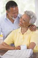 Couple relaxing with a newspaper smiling