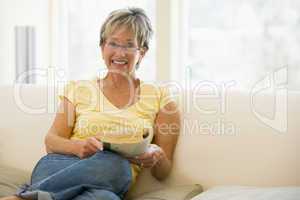 Woman relaxing with book in living room and smiling