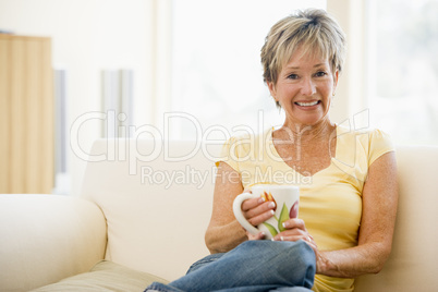 Woman sitting in living room with coffee smiling