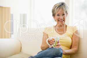 Woman sitting in living room with coffee smiling