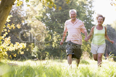 Couple running in park holding hands and smiling