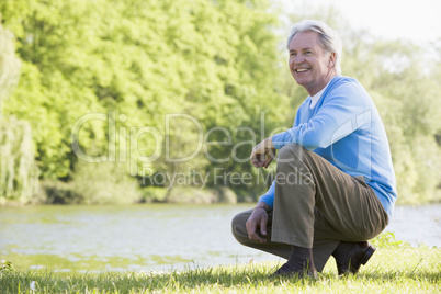 Man outdoors at park by lake smiling