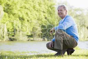 Man outdoors at park by lake smiling