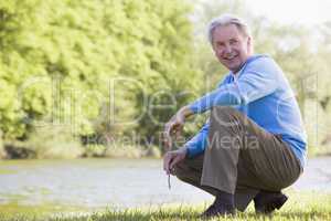 Man outdoors at park by lake smiling