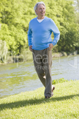 Man walking outdoors at park by lake smiling